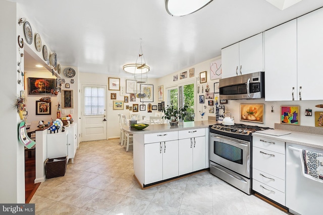 kitchen with light countertops, stainless steel appliances, white cabinets, and a peninsula