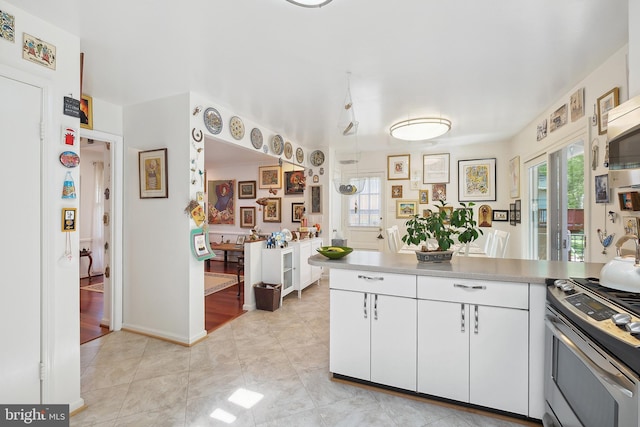 kitchen featuring white cabinetry, light tile patterned floors, a wealth of natural light, and gas stove