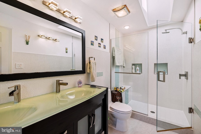 bathroom with double vanity, toilet, a sink, and a stall shower