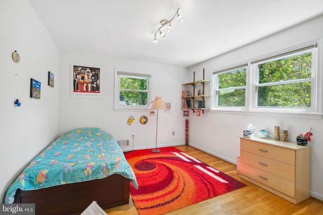 bedroom featuring baseboards, multiple windows, light wood-type flooring, and visible vents