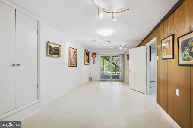 hall featuring wooden walls and rail lighting