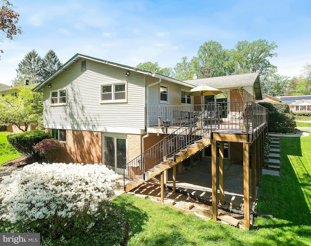 rear view of house with a lawn, a wooden deck, and stairway