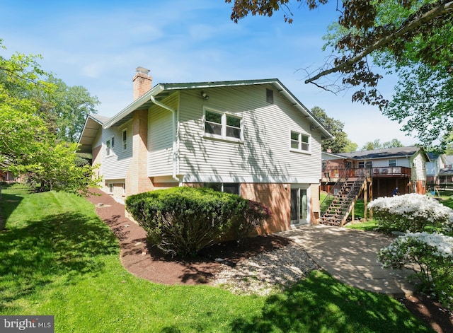 view of home's exterior featuring a deck, stairway, a chimney, a patio area, and a yard