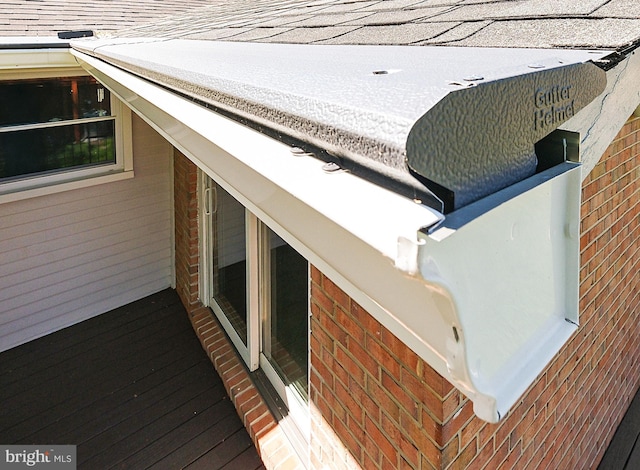 details featuring brick siding and roof with shingles
