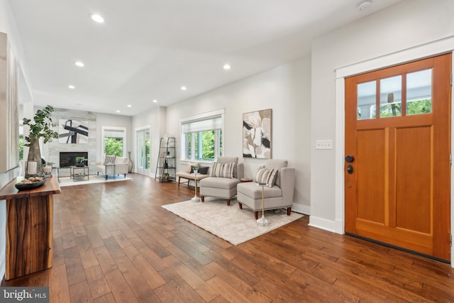 foyer entrance with recessed lighting, dark wood finished floors, baseboards, and a large fireplace