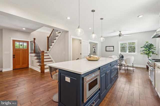 kitchen with light countertops, blue cabinets, dark wood-type flooring, and stainless steel appliances