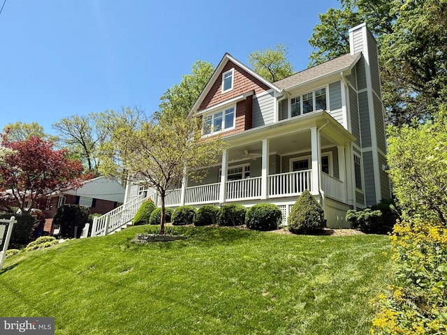 view of front of property with ceiling fan, covered porch, a front yard, a chimney, and stairway