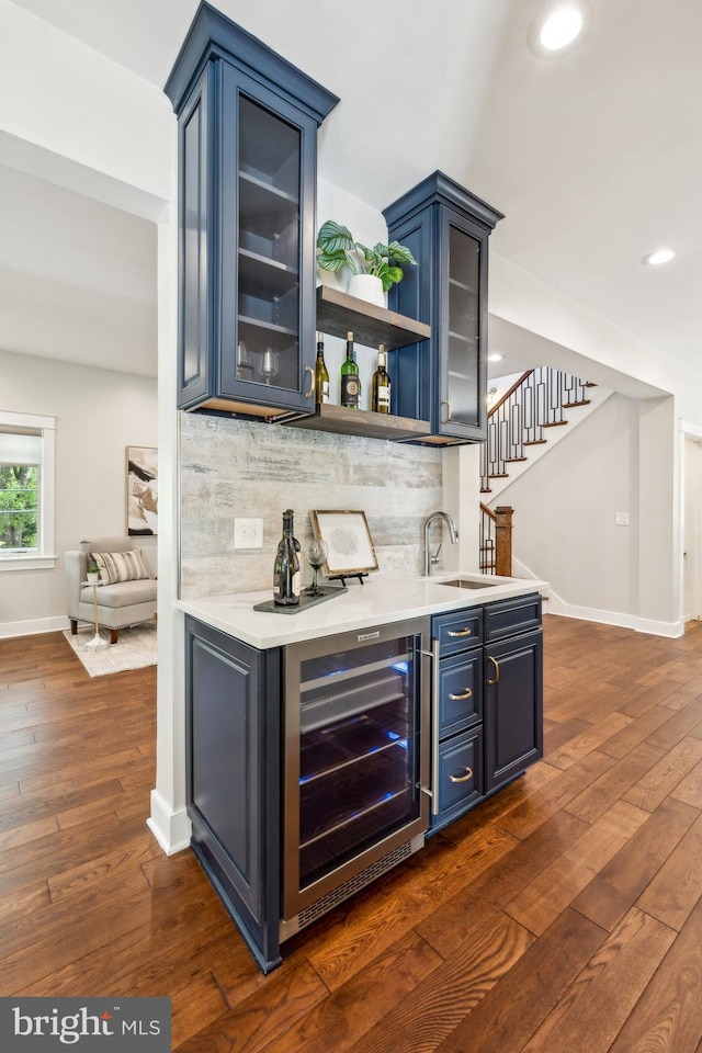 bar featuring dark wood-style flooring, a sink, baseboards, wet bar, and wine cooler
