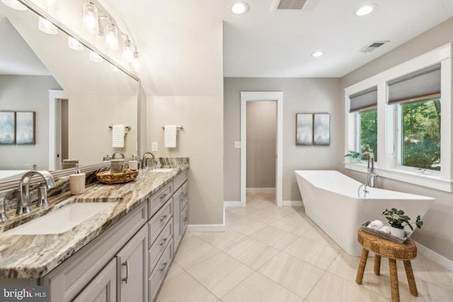 full bathroom with a sink, baseboards, a soaking tub, and visible vents