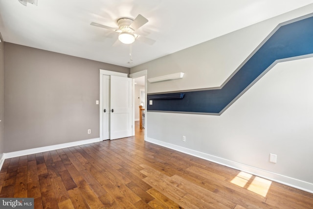 unfurnished room with baseboards, ceiling fan, and wood-type flooring