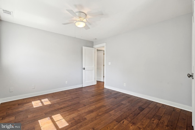 empty room with a ceiling fan, baseboards, visible vents, and dark wood finished floors