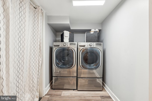 laundry room featuring washing machine and clothes dryer, laundry area, baseboards, and wood finished floors