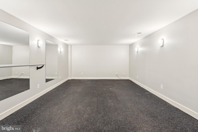 basement featuring baseboards and dark colored carpet