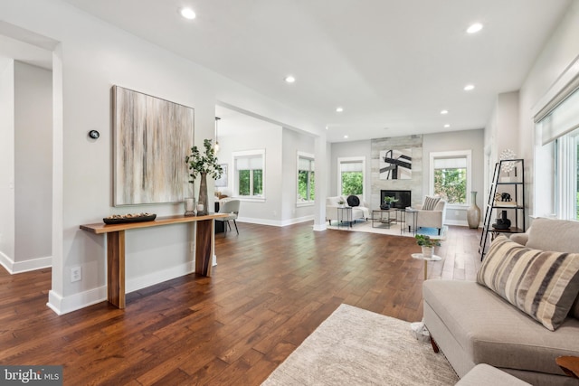 living area featuring recessed lighting, dark wood-style flooring, baseboards, and a large fireplace