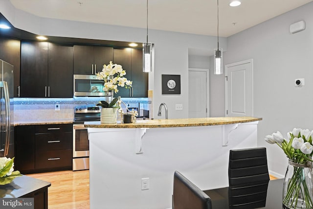 14184 Haro Trl, Gainesville, VA 20155 - kitchen with hanging light fixtures, appliances with stainless steel finishes, a kitchen breakfast bar, and light wood-style floors