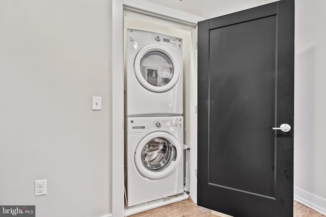 laundry room featuring stacked washer / drying machine, laundry area, and light wood-type flooring