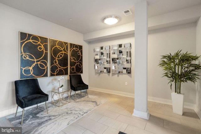 sitting room with baseboards, tile patterned flooring, decorative columns, and visible vents