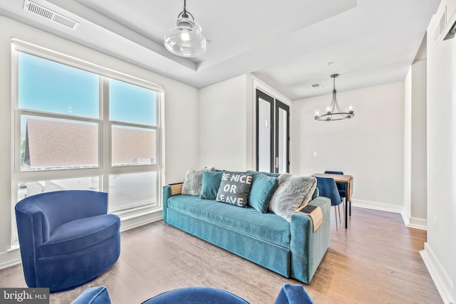 living area with baseboards, a notable chandelier, visible vents, and wood finished floors