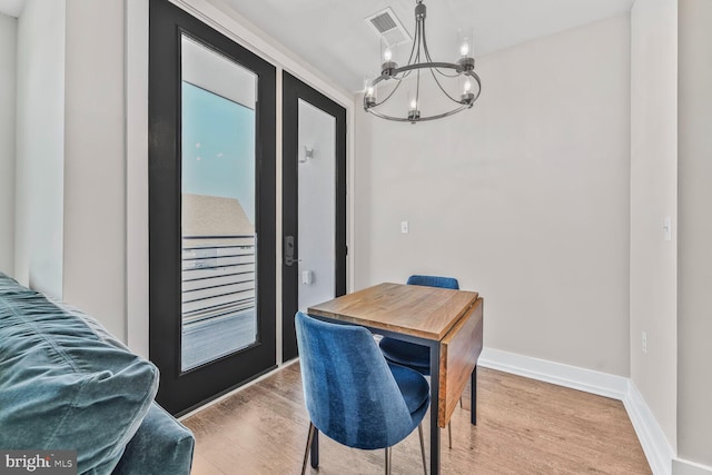 dining area featuring baseboards, a notable chandelier, light wood finished floors, and visible vents