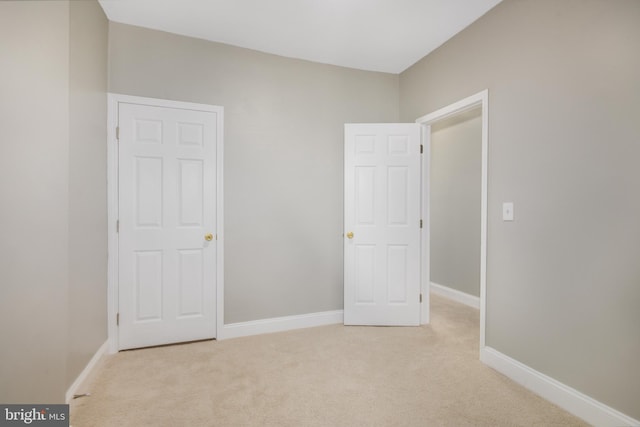 unfurnished bedroom featuring light colored carpet and baseboards