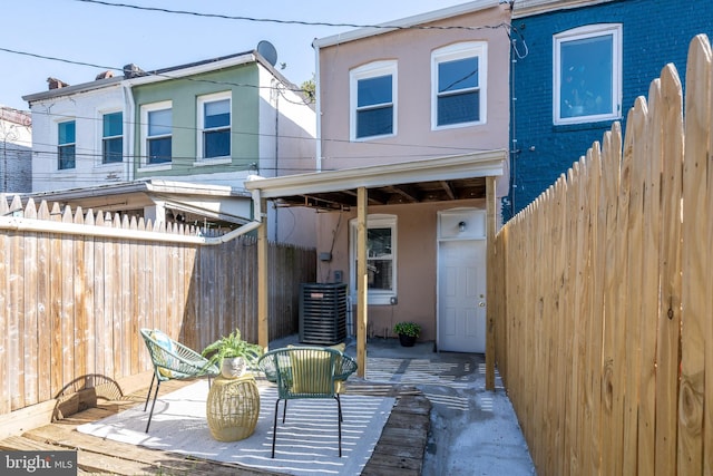 rear view of house with fence, a patio area, central AC, and stucco siding