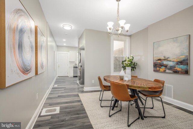 dining area featuring a chandelier, visible vents, baseboards, and dark wood-style flooring