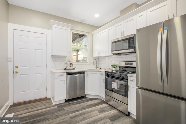 kitchen featuring stainless steel appliances, a sink, recessed lighting, white cabinetry, and light countertops
