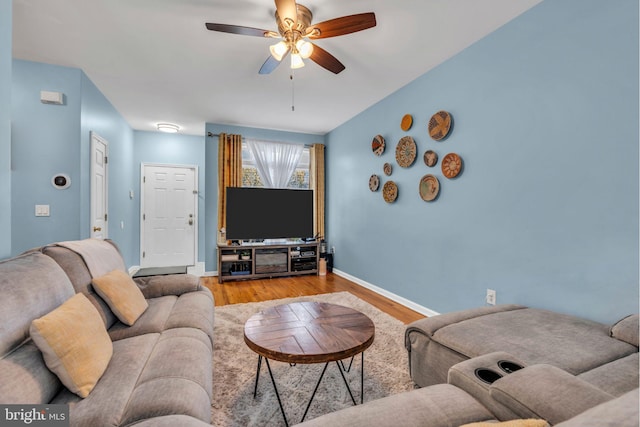 living area with baseboards, a ceiling fan, and wood finished floors