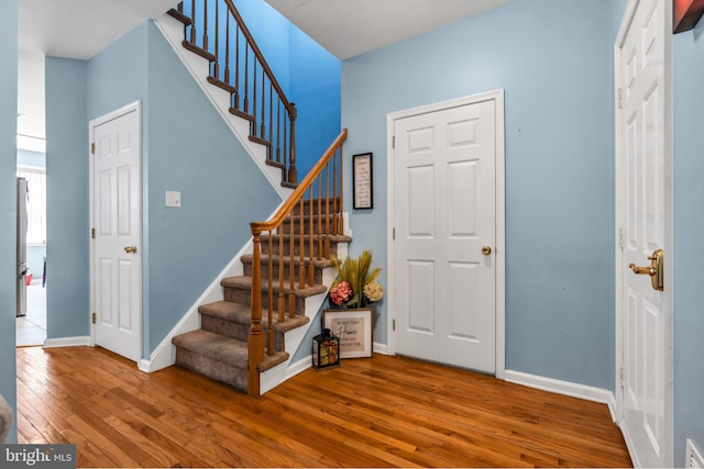 entryway with baseboards, visible vents, hardwood / wood-style floors, and stairway