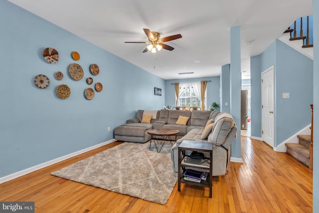 living area with baseboards, stairs, ceiling fan, and hardwood / wood-style floors