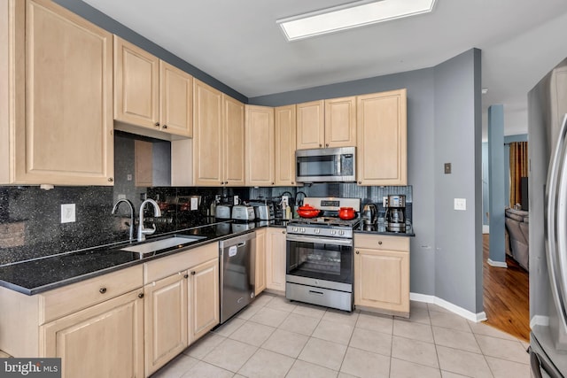 kitchen with light brown cabinetry, appliances with stainless steel finishes, tasteful backsplash, light tile patterned floors, and a sink