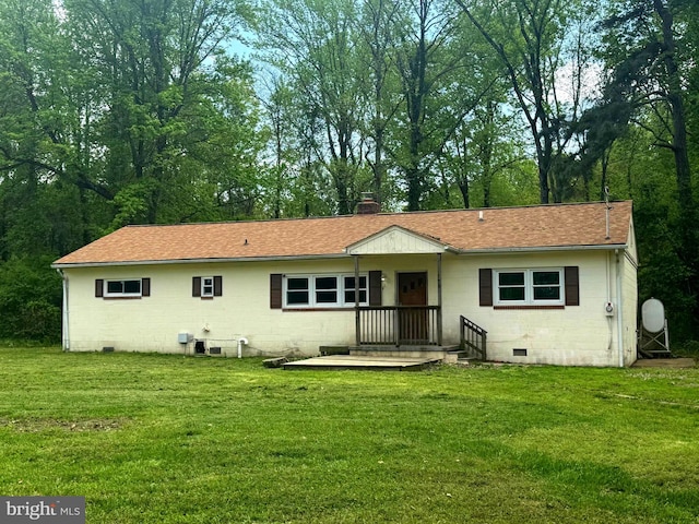 rear view of property featuring a lawn, roof with shingles, and concrete block siding