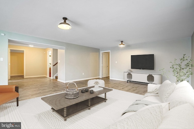 living area featuring wood finished floors, stairway, and baseboards