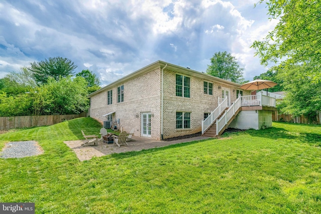 rear view of house featuring stairway, brick siding, a wooden deck, a patio, and a fire pit
