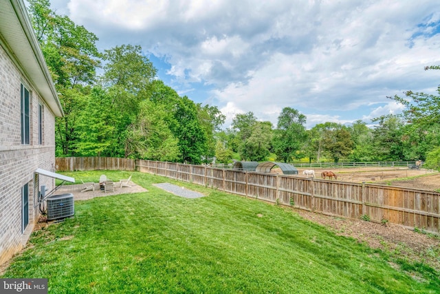 view of yard featuring central AC, a fire pit, and a patio area