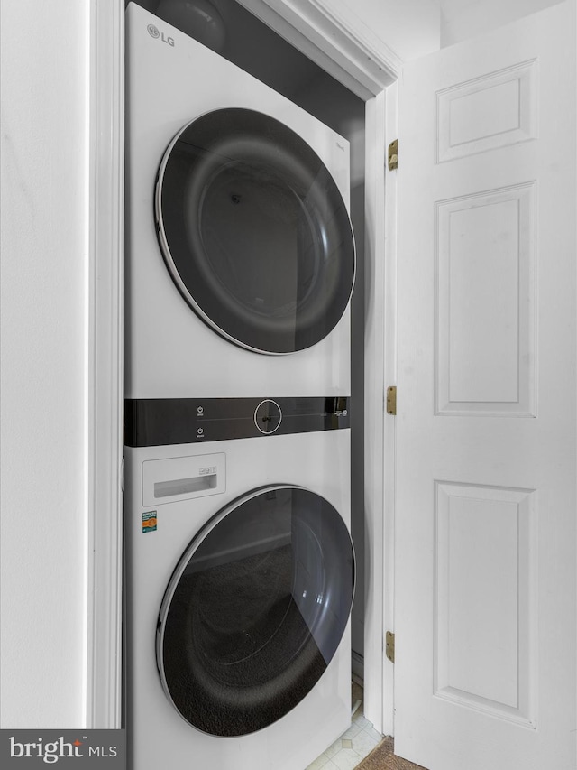 clothes washing area featuring stacked washer / dryer and laundry area
