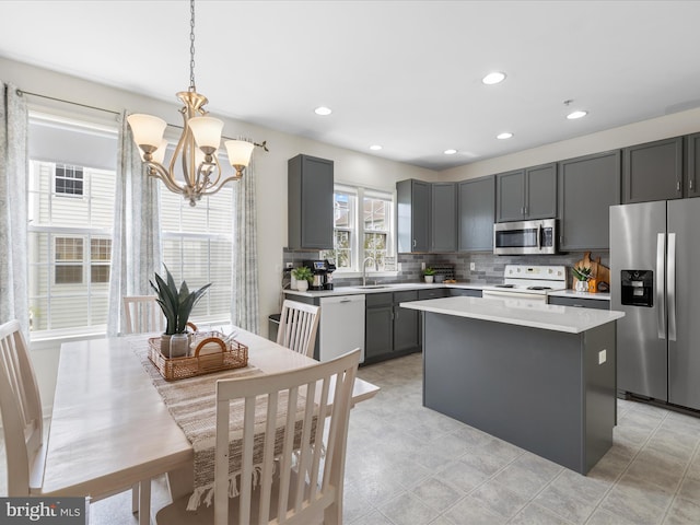kitchen with decorative backsplash, a sink, appliances with stainless steel finishes, light countertops, and an inviting chandelier