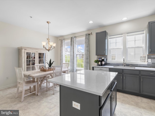 kitchen featuring light stone countertops, an inviting chandelier, a sink, a center island, and hanging light fixtures