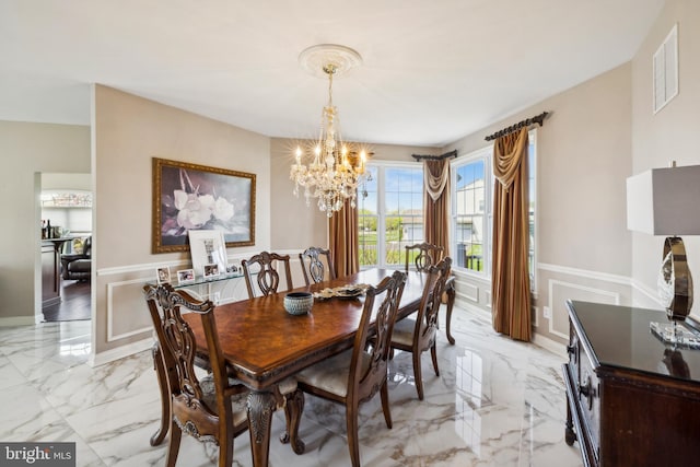 dining area with an inviting chandelier, a decorative wall, marble finish floor, and visible vents