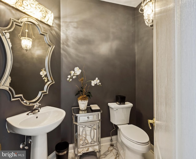 half bath featuring baseboards, a sink, marble finish floor, and toilet
