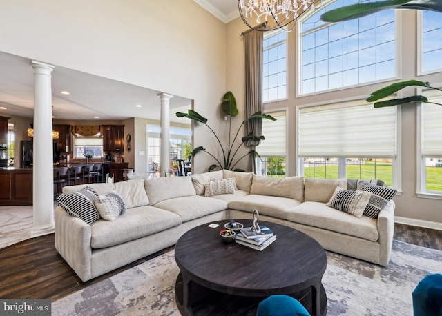 living area with ornate columns, crown molding, and wood finished floors