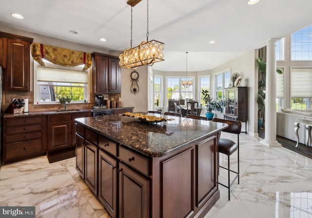 kitchen featuring ornate columns, a wealth of natural light, a sink, and marble finish floor