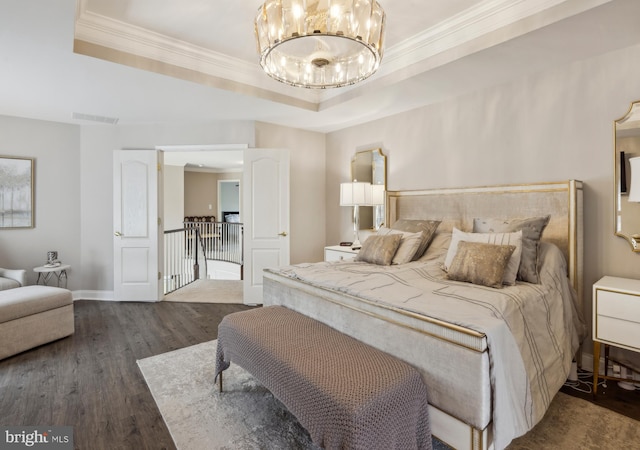bedroom with visible vents, wood finished floors, a raised ceiling, an inviting chandelier, and ornamental molding