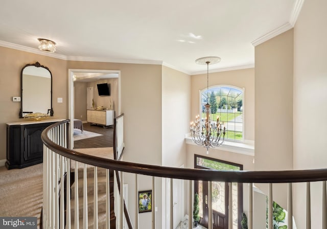 hallway with ornamental molding, an upstairs landing, and a chandelier