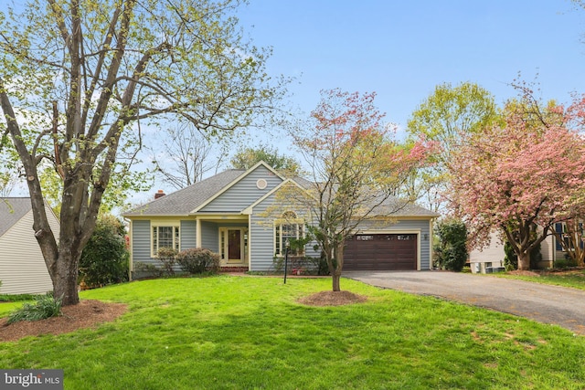 view of front facade featuring an attached garage, aphalt driveway, and a front yard