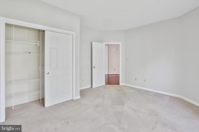 unfurnished bedroom featuring baseboards, carpet floors, and a closet