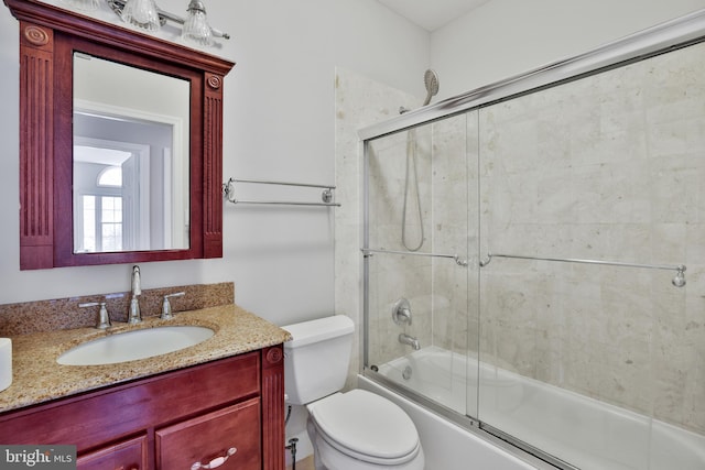 bathroom featuring vanity, enclosed tub / shower combo, and toilet