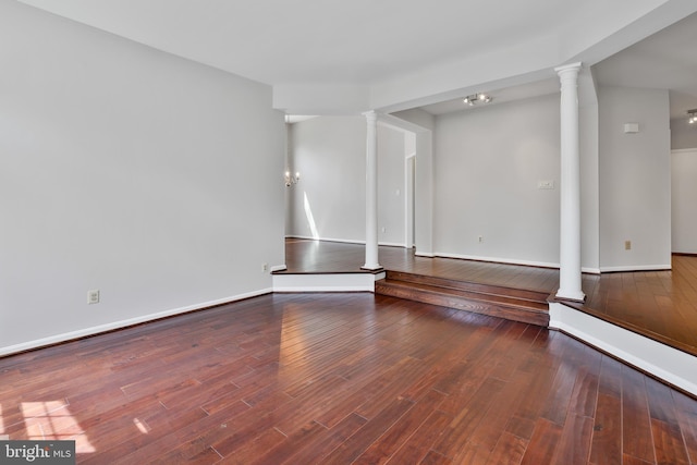 unfurnished living room with baseboards, wood finished floors, and decorative columns