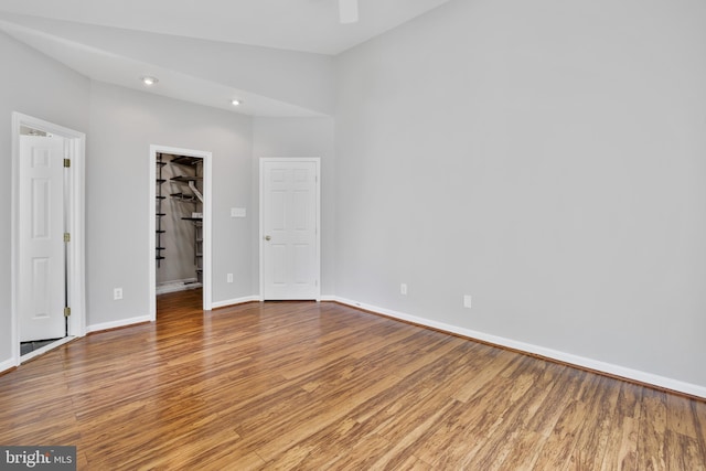 unfurnished bedroom with a spacious closet, baseboards, wood finished floors, and recessed lighting
