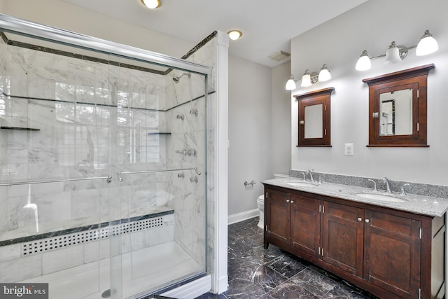 bathroom featuring double vanity, marble finish floor, toilet, and a sink